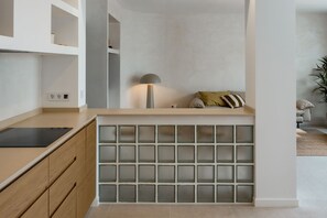 Eine Küche mit integrierter Kochinsel, Holzschränken und einer Wand aus Glasbausteinen.