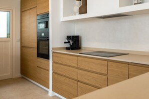 Eine moderne Küche mit eingebauten Geräten, einer Kaffeemaschine und einem Tablet auf der Arbeitsplatte.