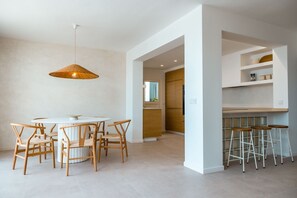 Eine moderne Küche mit weißen Schränken, einem runden Esstisch mit Holzstühlen und einer Pendelleuchte.