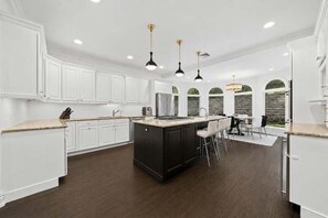 Una cocina moderna con armarios blancos, una isla central e iluminación colgante.
