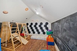 A room with a wooden play structure, a hexagonal wall pattern, and a chalkboard with writing. - Elevated Luxury Living with Sweeping NYC Skyline Views 6-bed house in Montclair (Montclair)