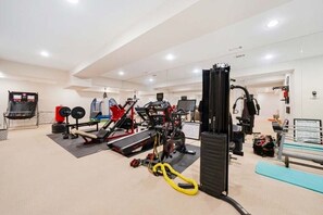 Un gimnasio con diversos equipos de ejercicio, incluyendo cintas de correr, máquinas de pesas y bandas de resistencia.