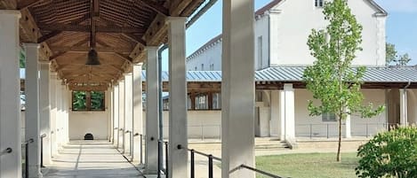 A covered walkway with columns and a view of a building in the background.