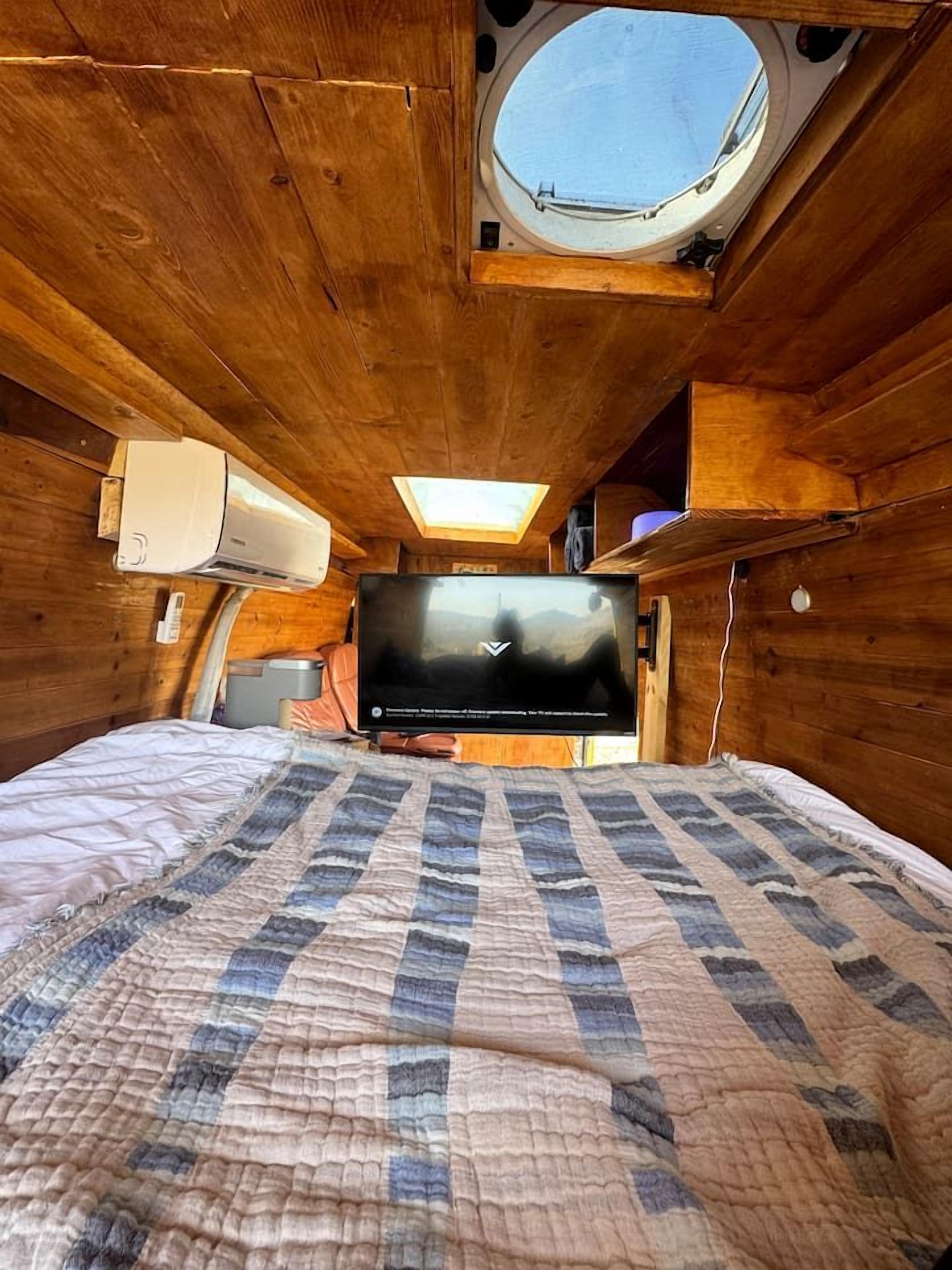 Une pièce confortable avec un lit, une télévision, une lucarne et une fenêtre.