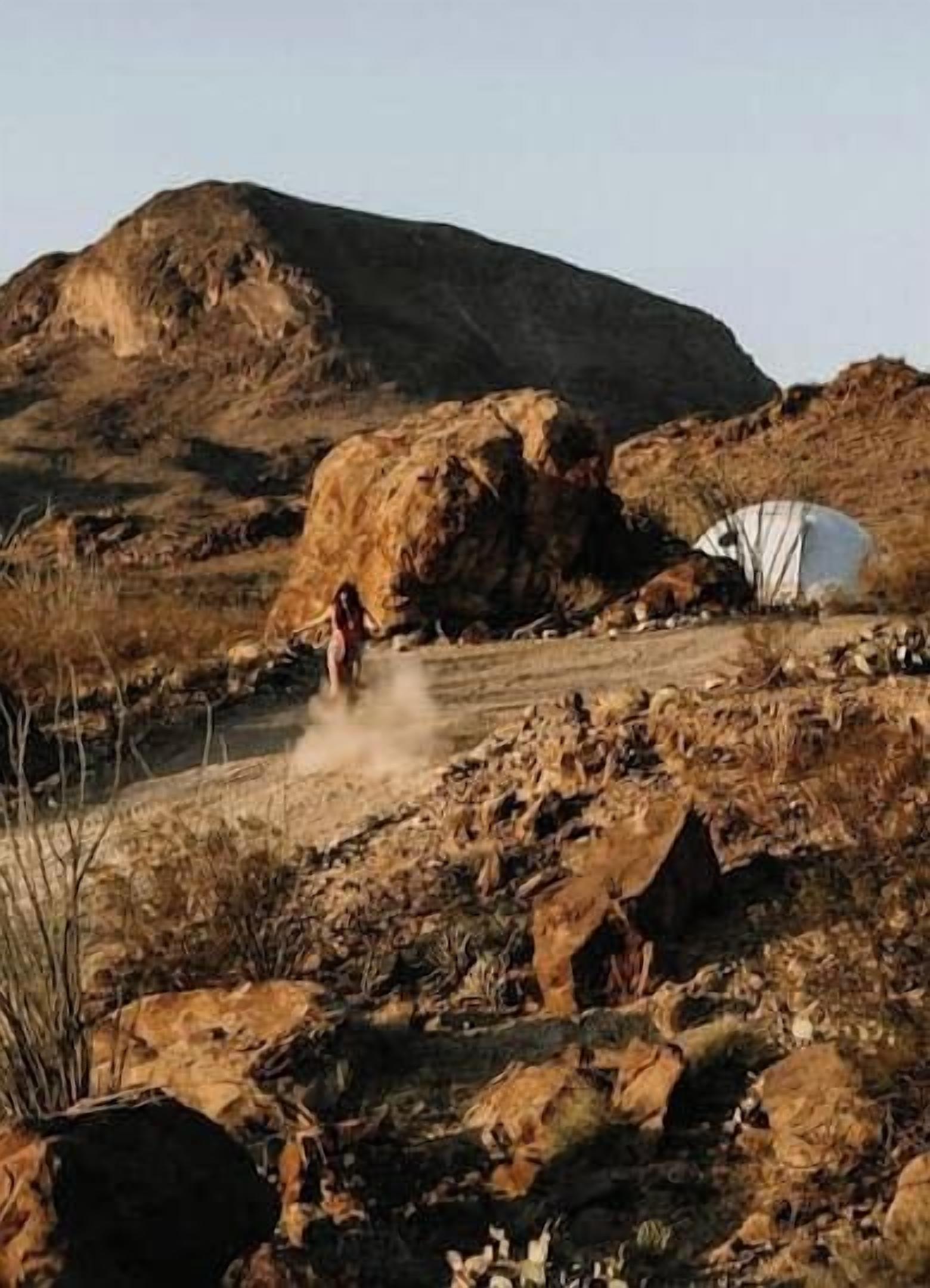 A rugged outdoor setting with a tent and rocky terrain.