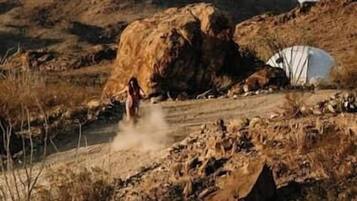 A rugged outdoor setting with a tent and rocky terrain.