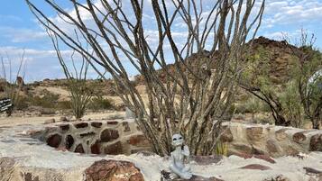 A desert landscape with a rock formation and a small alien figure.