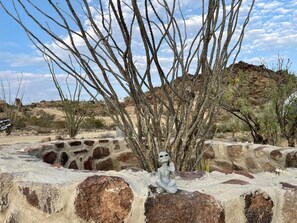 Un paysage désertique avec une formation rocheuse et une petite figurine d’extraterrestre.