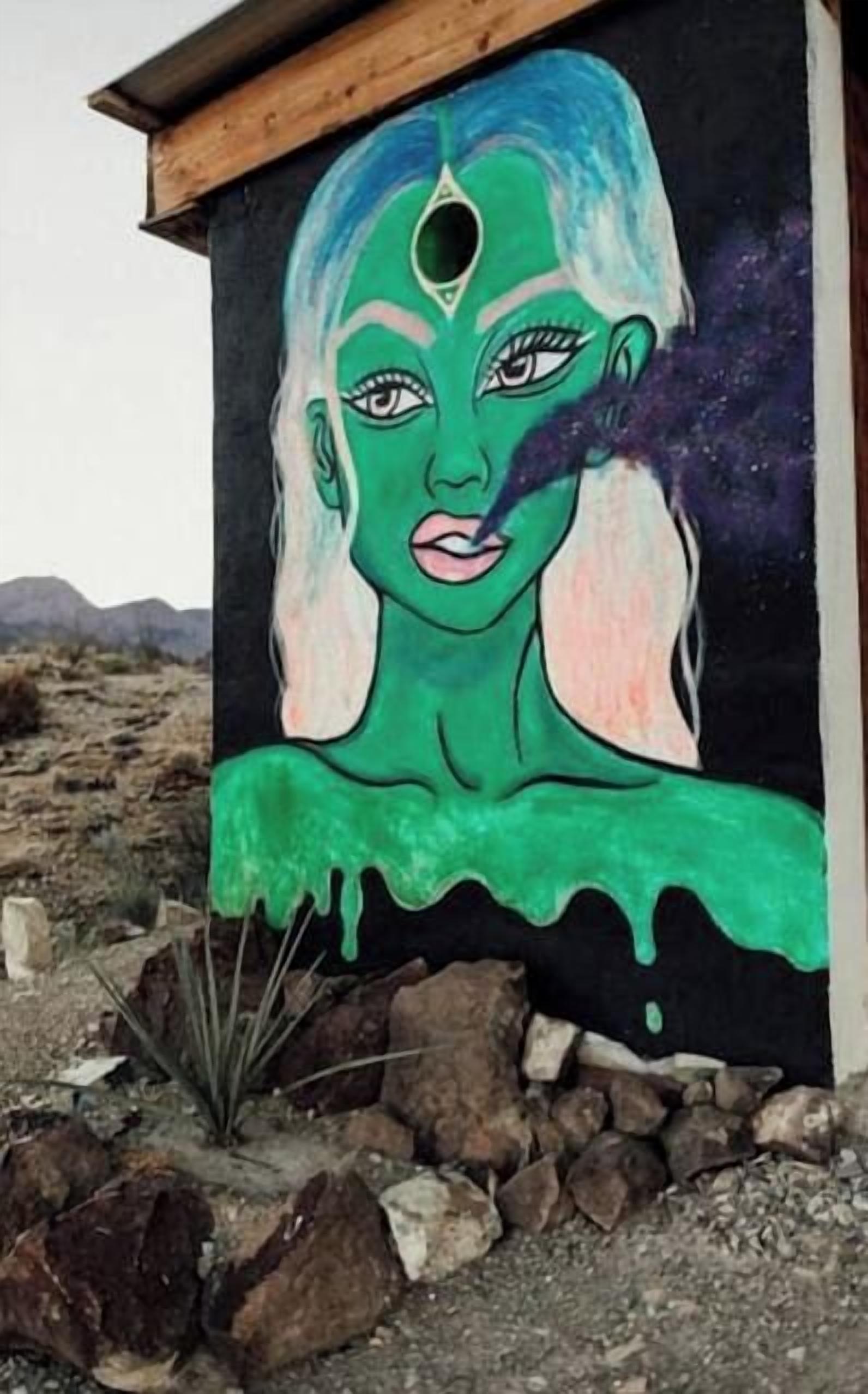 A building with a mural of a woman with green hair and a black background.
