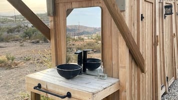 A wooden structure with a table and a window, surrounded by a desert landscape.