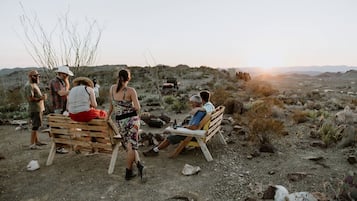 A group of people sitting on wooden benches outdoors with a desert landscape in the background.