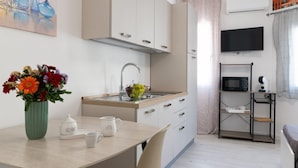 A compact kitchen with a sink, microwave, and a small dining area with a table and chairs. - Cozy 14 sqm studio apartment, ideal for one person, located on the second floor of a renovated historic building (no elevator). The property enjoys a strategic location just steps away from the Policlinico hospital, the Ballarò district, and the city ce (Palermo)