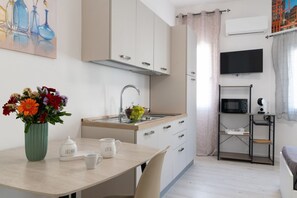 A compact kitchen with a sink, microwave, and a small dining area with a table and chairs. - Cozy 14 sqm studio apartment, ideal for one person, located on the second floor of a renovated historic building (no elevator). The property enjoys a strategic location just steps away from the Policlinico hospital, the Ballarò district, and the city ce (Palermo)