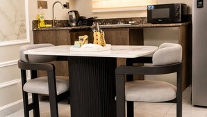 Uma cozinha moderna com uma mesa de jantar redonda, duas cadeiras, um micro-ondas e uma chaleira.