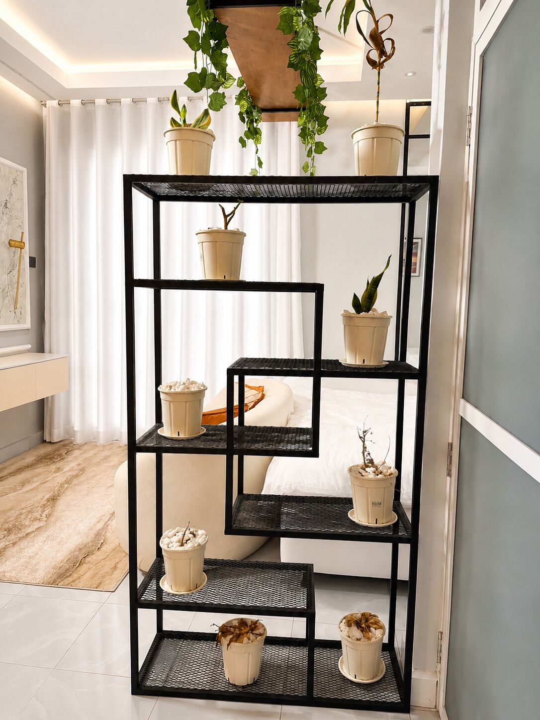 A multi-tiered black metal shelf unit with potted plants and decorative items.
