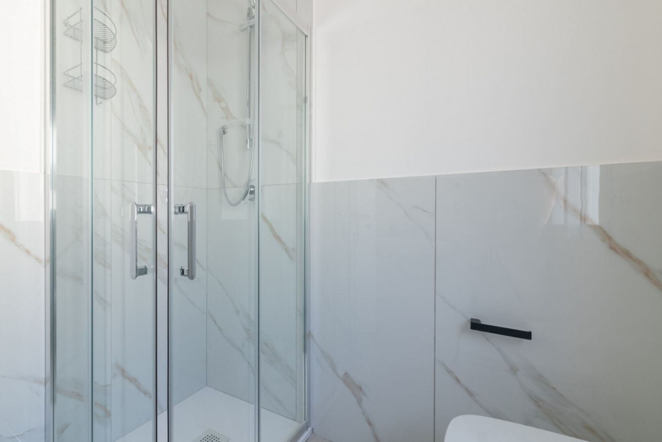 Een moderne badkamer met een douchecabine van glas, marmeren wanden en een minimalistisch design.