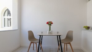 Een eethoek met een tafel, twee stoelen, een vaas met bloemen en een raam.
