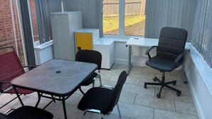 Een oranjerie met een tafel, stoelen en een geel kastje.