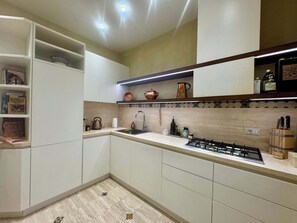 A modern kitchen with white cabinets, a gas stove, and a countertop with various kitchen items. - Chic Rome Apartment, Master + Bonus Study/Bedroom (Roma)