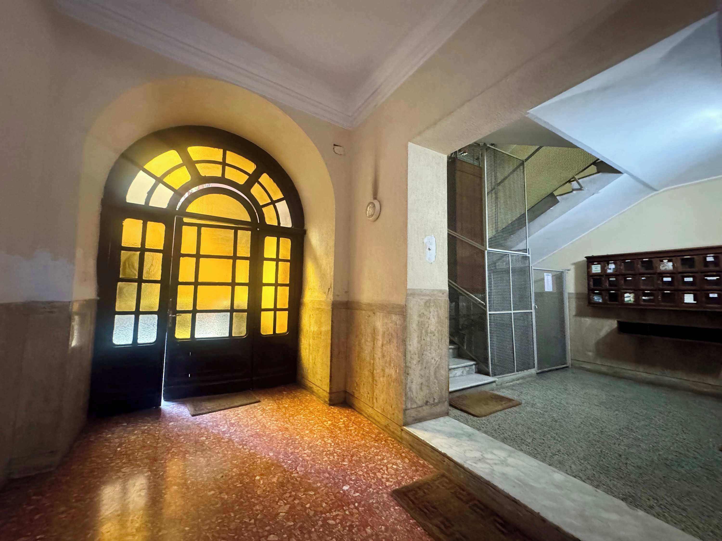 An interior corridor with a large arched doorway leading to a stairwell.