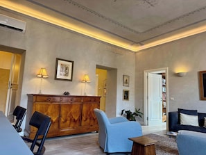 Ein geräumiges Wohnzimmer mit einem Holzkabinett, zwei Sesseln, einem Sofa und einem Couchtisch.