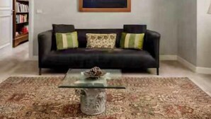 A living room with a black sofa, a glass coffee table, and a patterned rug. - Chic Rome Apartment, Master + Bonus Study/Bedroom (Roma)