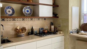 A kitchen with white cabinets, a stove, and copper cookware on shelves. - Chic Rome Apartment, Master + Bonus Study/Bedroom (Roma)