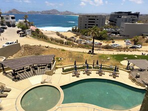 Ett semesterhotell med en swimmingpool, solstolar och utsikt över havet.