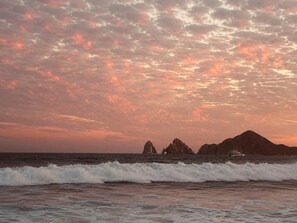 A coastal landscape with waves and a sunset sky. - Beachfront Arch View Balcony, Pool & Resort Access (Cabo San Lucas)