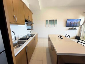 Une cuisine moderne avec des meubles en bois, un four à micro-ondes encastré et un grand îlot central doté de chaises.