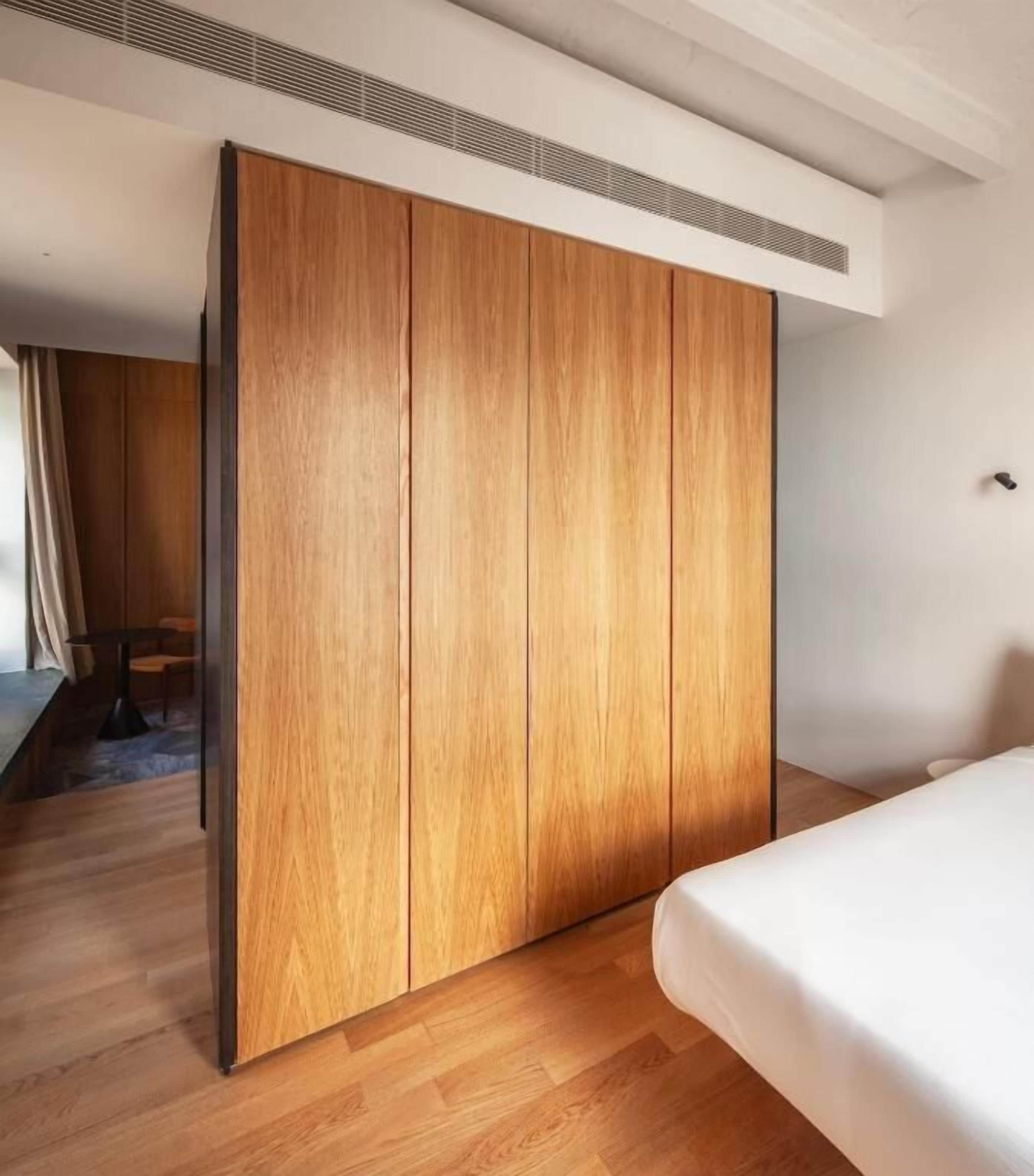 Un dormitorio con un armario de madera, una cama y un respiradero en el techo.