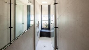 A narrow, modern hallway with glass doors leading to a bathroom.