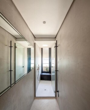 Un pasillo moderno y estrecho con puertas de vidrio que dan a un baño.