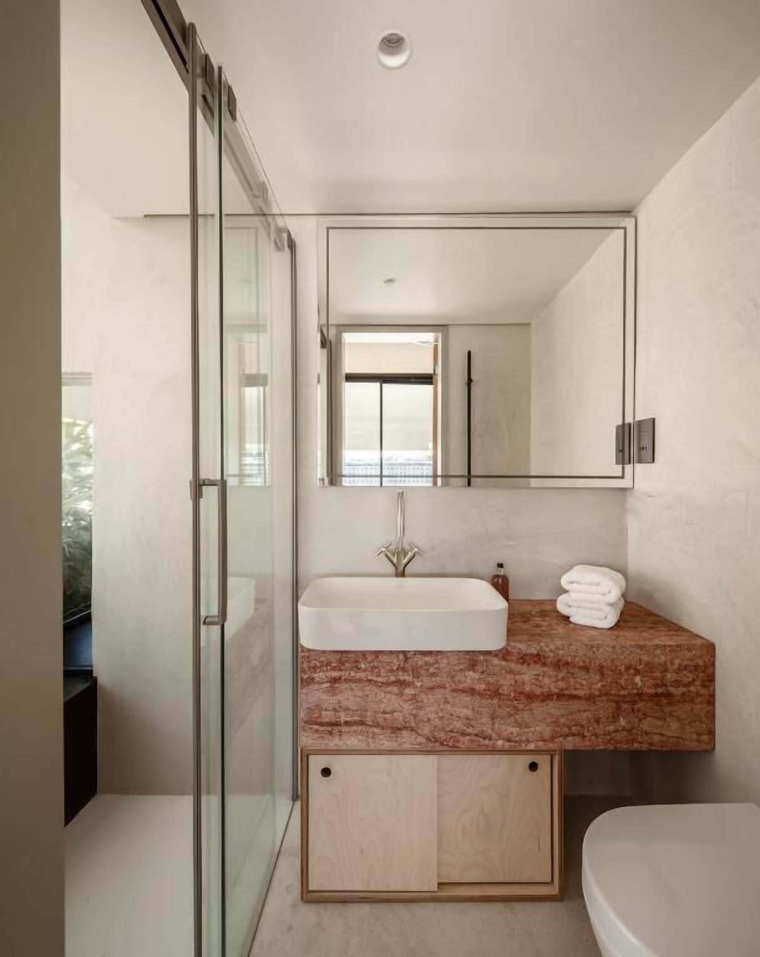 Un bagno moderno con box doccia in vetro, lavabo con piano in marmo e servizi igienici.