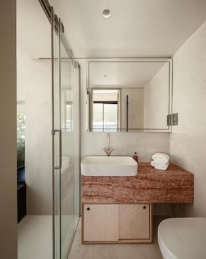 Ein modernes Badezimmer mit Duschkabine aus Glas, Marmorwaschtisch und Toilette.