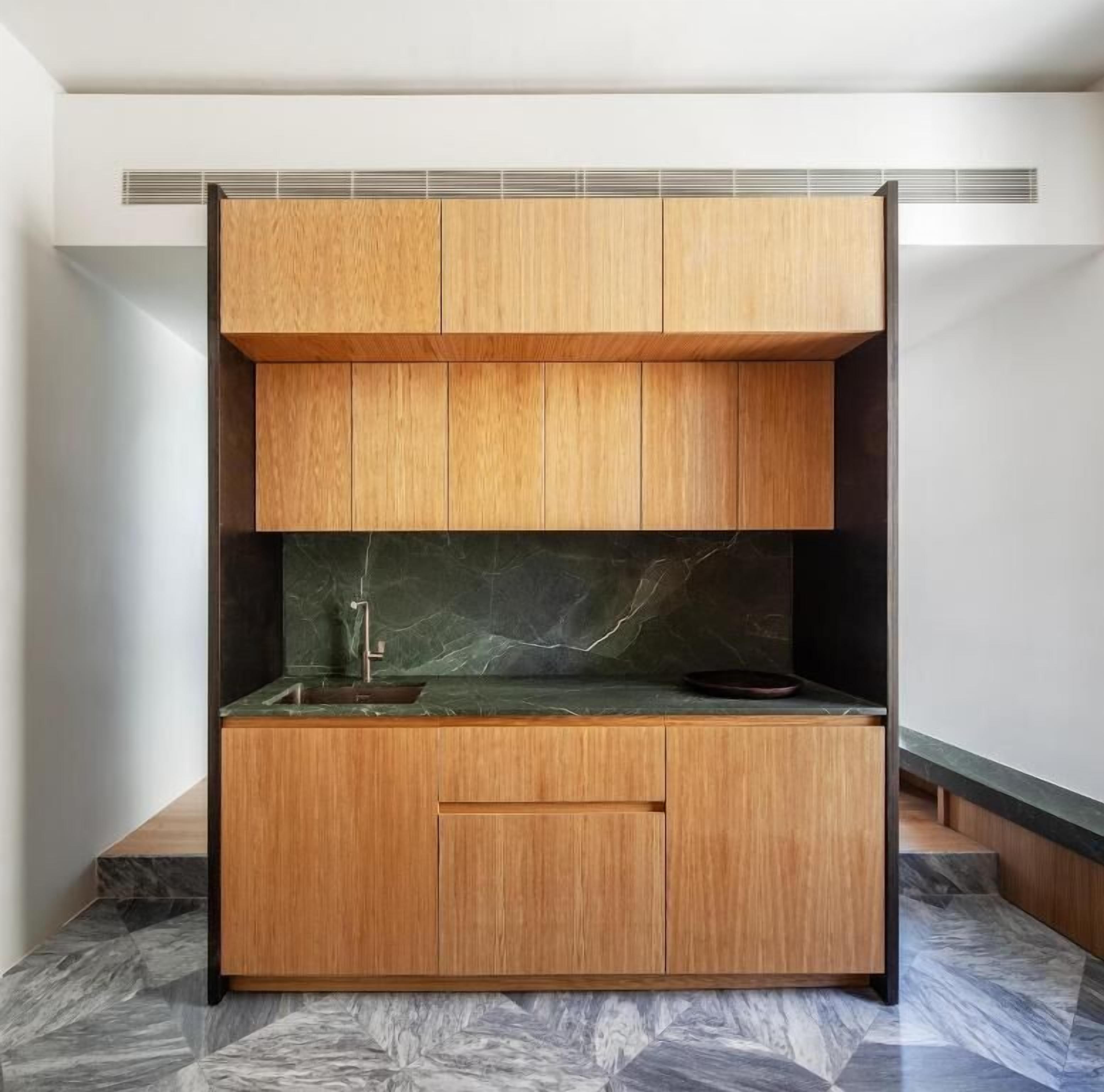 A modern kitchen with wooden cabinetry, a marble backsplash, and a built-in sink.