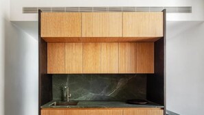 A modern kitchen with wooden cabinetry, a marble backsplash, and a built-in sink.
