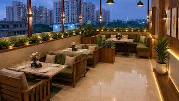 A rooftop restaurant with outdoor seating, large windows, and city views.