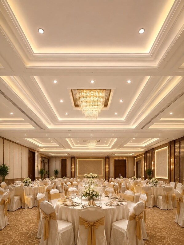 Un salón de banquetes con mesas redondas, sillas y una araña de cristal.