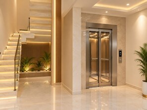 A modern elevator with a metallic finish, a staircase with illuminated steps, and a potted plant to the right. - Hotel Ocean Pearl (Agra)