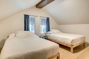 A room with two beds, wooden flooring, and a sloped ceiling. - Nayati Chalet | Luxury Chalet with Spa Near Mont-Tremblant (Amherst)