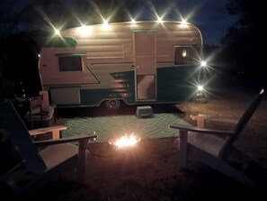 Una autocaravana con un pozo de fuego y dos sillas.