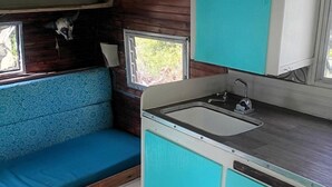 A compact kitchen with a sink, a window, and a blue cabinet. - Vintage Shasta Camper with Relaxing Fire Pit Escape on Geyserville, California (Geyserville)