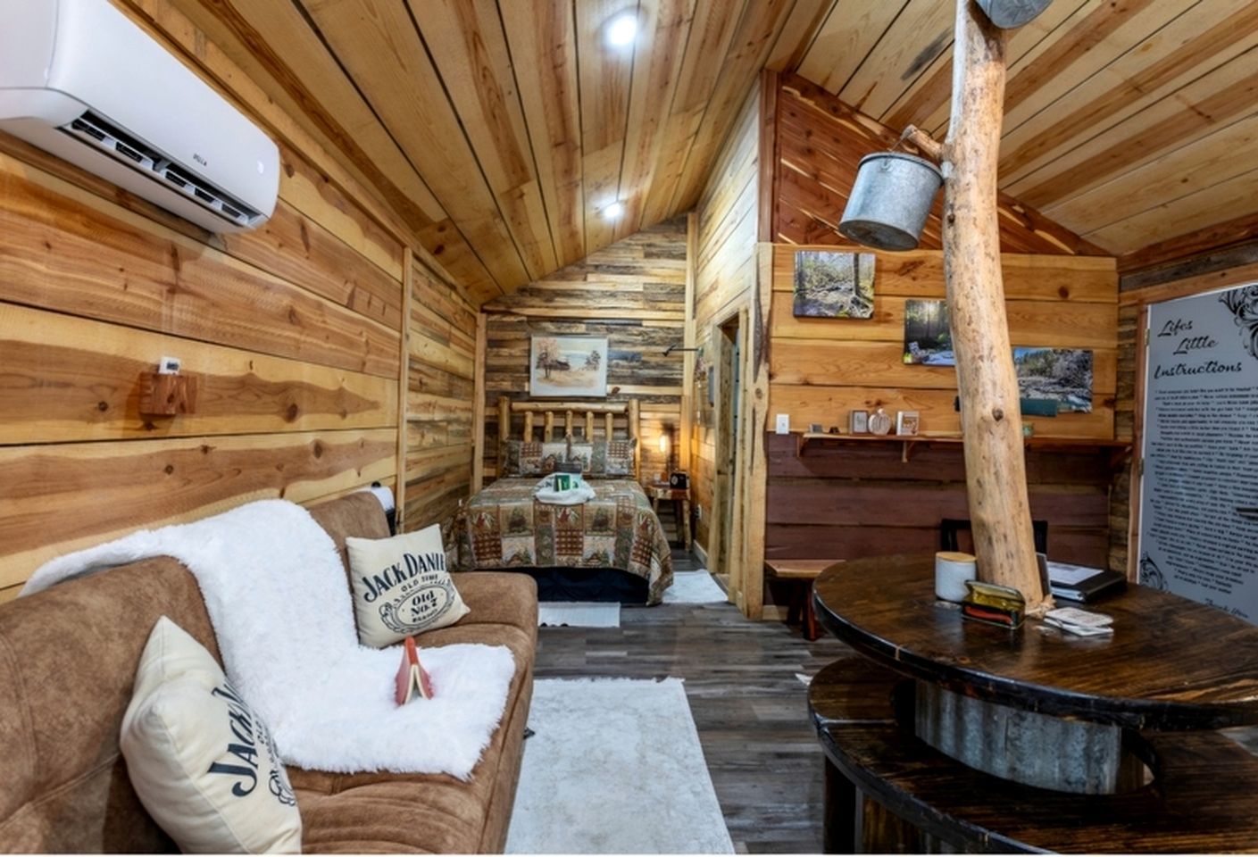 A cozy cabin interior with a wooden interior, a couch with a blanket, a table, and a fireplace.