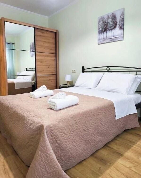 Ein Schlafzimmer mit einem Bett, einem Nachttisch, einem Spiegel und einem Bild an der Wand.