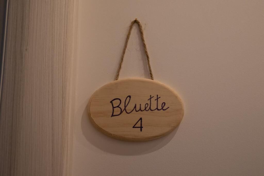 A wooden plaque with the name 'Bluette 4' hanging on a wall.
