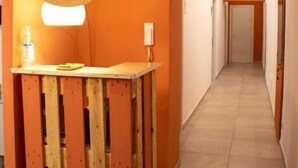 Un pasillo con un banco de madera, un sombrero y una lámpara.