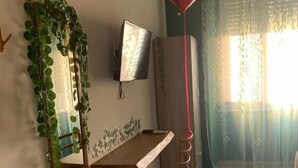 A dining area with a wooden table and chairs, a mirror, a potted plant, and a red heart-shaped balloon. - Rallegranza (Naples)