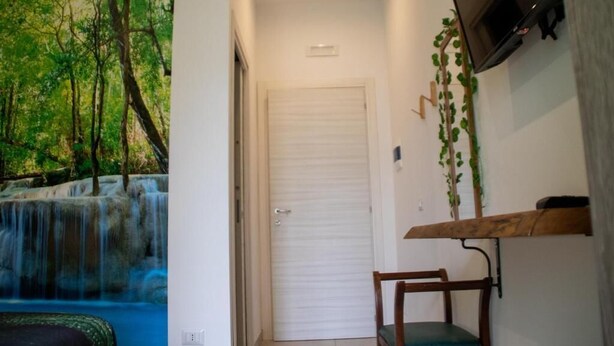 A hallway with a door, a mounted TV, and a wooden bench. - Rallegranza (Naples)