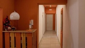 Un pasillo con un mostrador de recepción de madera, una lámpara blanca y un equipo de aire acondicionado en la pared.